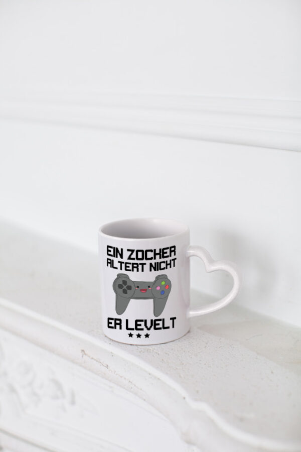 Ein Zocker altert nicht, er levelt - Herzhenkel Tasse - Kaffeetasse / Geschenk / Familie