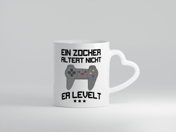 Ein Zocker altert nicht, er levelt - Herzhenkel Tasse - Kaffeetasse / Geschenk / Familie